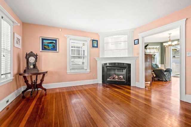 living room with a wealth of natural light, hardwood / wood-style floors, and a chandelier