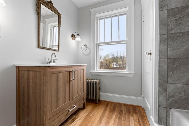 bathroom with radiator, baseboards, vanity, and wood finished floors