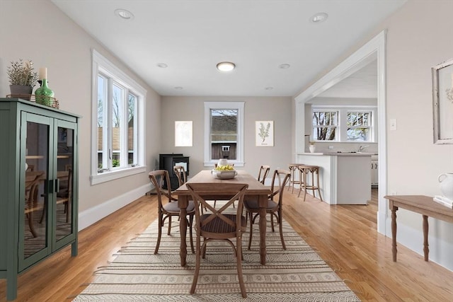 dining space with light wood-type flooring, baseboards, and a healthy amount of sunlight