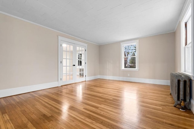 unfurnished room featuring radiator, ornamental molding, french doors, and light wood-style flooring