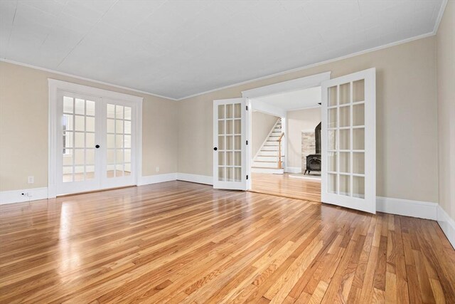 unfurnished room featuring light wood-style floors, crown molding, baseboards, and french doors