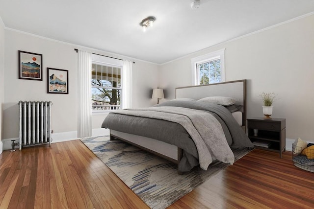 bedroom featuring radiator, wood finished floors, baseboards, and ornamental molding