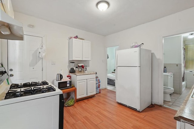 kitchen featuring white appliances, exhaust hood, light hardwood / wood-style flooring, tile walls, and white cabinetry