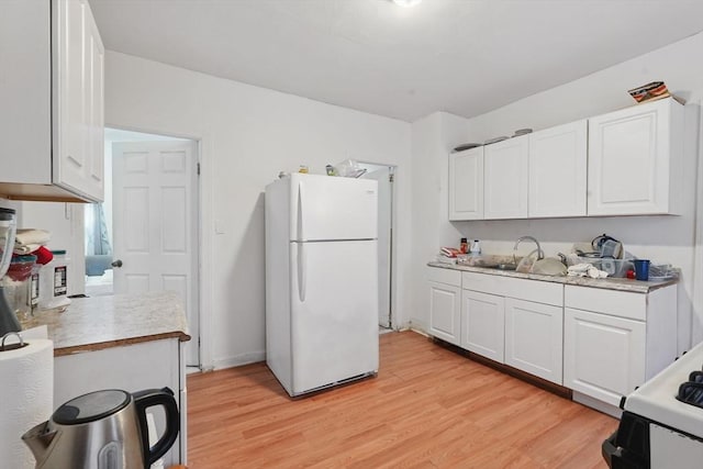 kitchen featuring light wood-type flooring, sink, range, white fridge, and white cabinetry