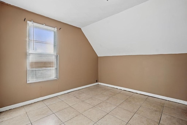 bonus room with light tile patterned flooring and vaulted ceiling