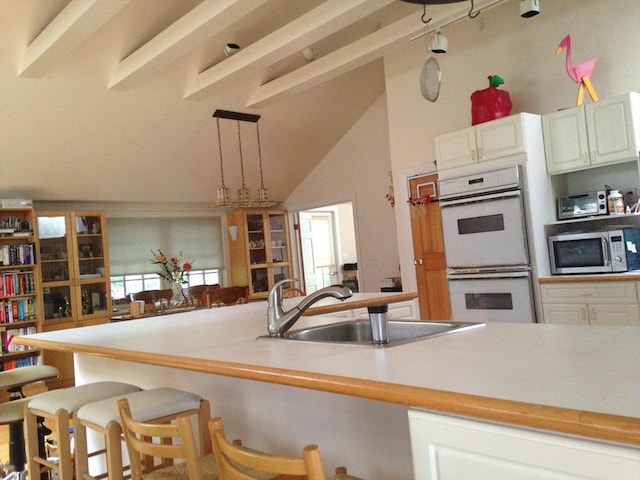 12 Inis Cir, Newton, MA 02465 - kitchen featuring double oven, a sink, stainless steel microwave, a kitchen breakfast bar, and light countertops