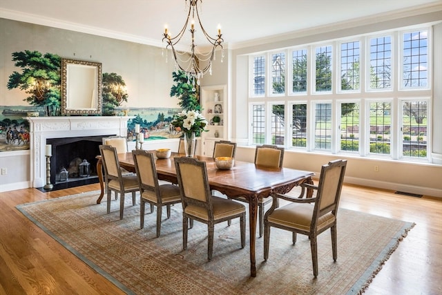 dining area with light hardwood / wood-style floors, an inviting chandelier, and ornamental molding