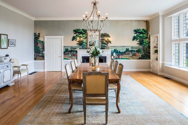 dining area with a wealth of natural light, a notable chandelier, crown molding, and hardwood / wood-style flooring