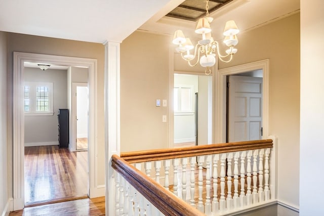 hall featuring hardwood / wood-style floors, ornamental molding, a chandelier, and a tray ceiling