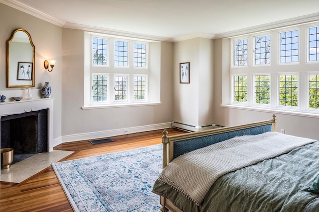 bedroom with hardwood / wood-style floors, crown molding, and baseboard heating