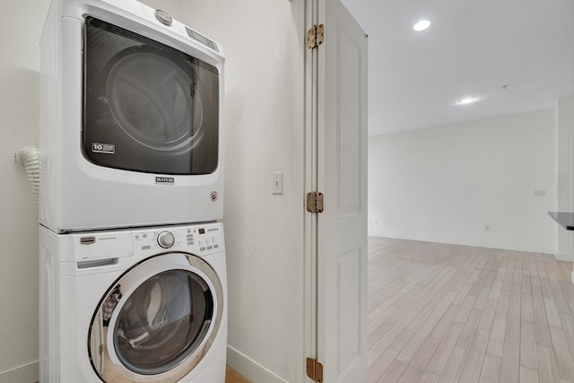 laundry room featuring light hardwood / wood-style flooring and stacked washer / dryer