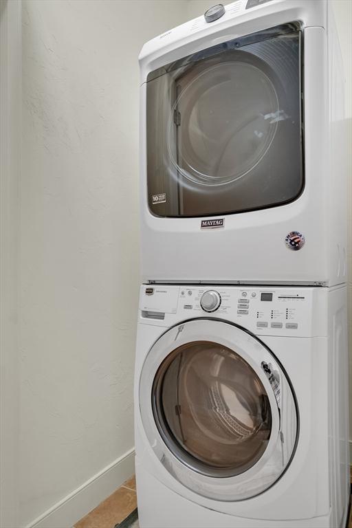 washroom with tile patterned floors and stacked washer and dryer