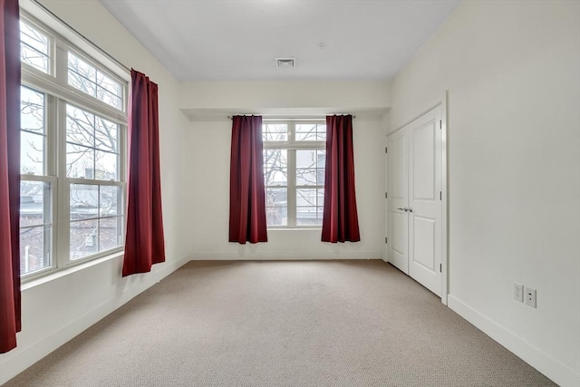 empty room featuring a wealth of natural light and light carpet