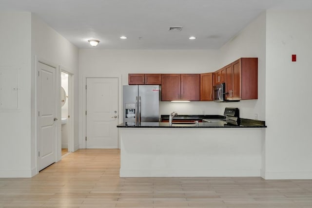 kitchen with appliances with stainless steel finishes, dark stone countertops, sink, kitchen peninsula, and electric panel