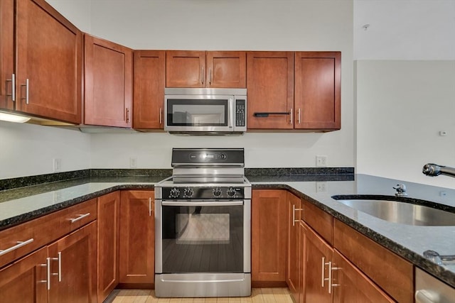 kitchen with sink, range, and dark stone counters