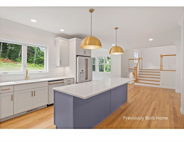 kitchen featuring light wood-type flooring, white appliances, sink, a center island, and hanging light fixtures