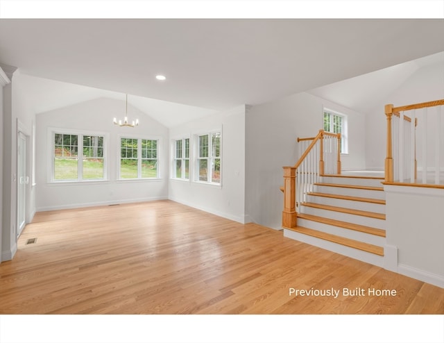 unfurnished living room featuring a notable chandelier, light wood-type flooring, and lofted ceiling