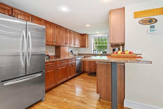 9 Emerson Ct, Winchester, MA 01890 - kitchen with appliances with stainless steel finishes, light wood finished floors, brown cabinets, light stone countertops, and a peninsula