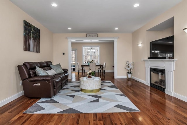 living area featuring recessed lighting, a glass covered fireplace, dark wood finished floors, and baseboards