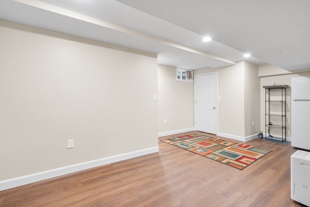 basement with wood-type flooring and white fridge