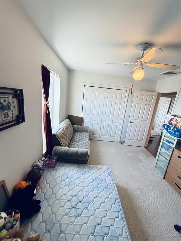 sitting room with carpet floors, ceiling fan, and visible vents