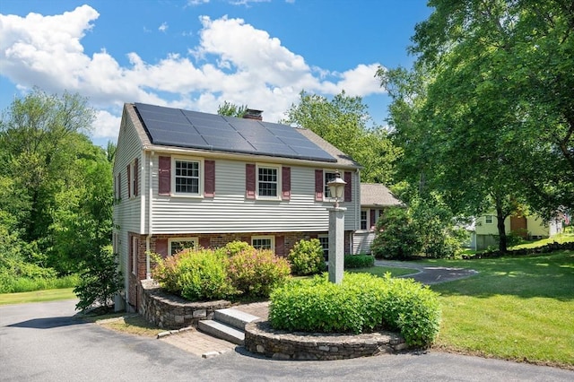 241 W Main St, Westborough, MA 01581 - view of front of property with roof mounted solar panels, a front yard, and a chimney