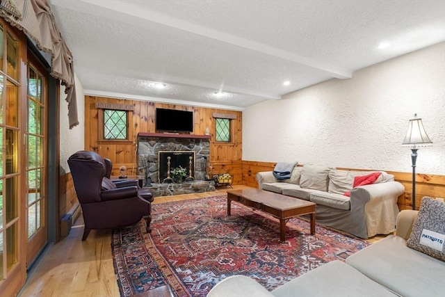 369 Border Rd, Concord, MA 01742 - living area with a textured ceiling, wooden walls, a textured wall, wood finished floors, and a stone fireplace