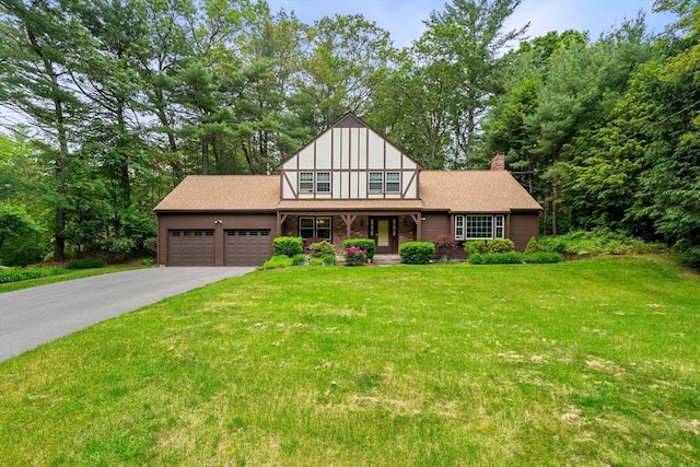 369 Border Rd, Concord, MA 01742 - tudor-style house featuring an attached garage, asphalt driveway, a porch, a front yard, and a chimney