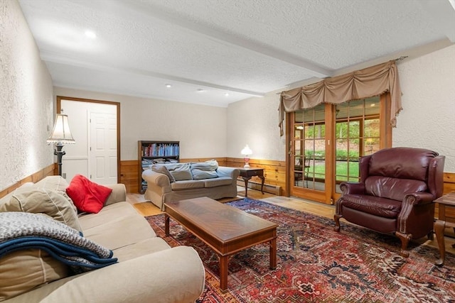 369 Border Rd, Concord, MA 01742 - living area featuring a textured ceiling, a baseboard heating unit, a wainscoted wall, wood walls, and wood finished floors