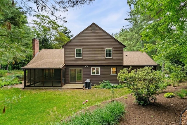 369 Border Rd, Concord, MA 01742 - back of property featuring a sunroom, a chimney, a patio area, a yard, and a shingled roof