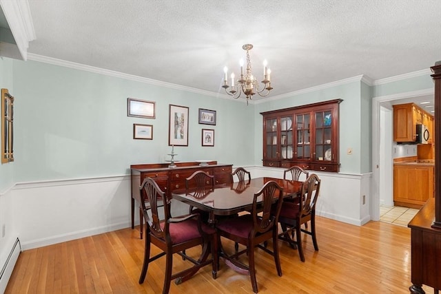 369 Border Rd, Concord, MA 01742 - dining area featuring a chandelier, light wood-style flooring, baseboard heating, ornamental molding, and a textured ceiling