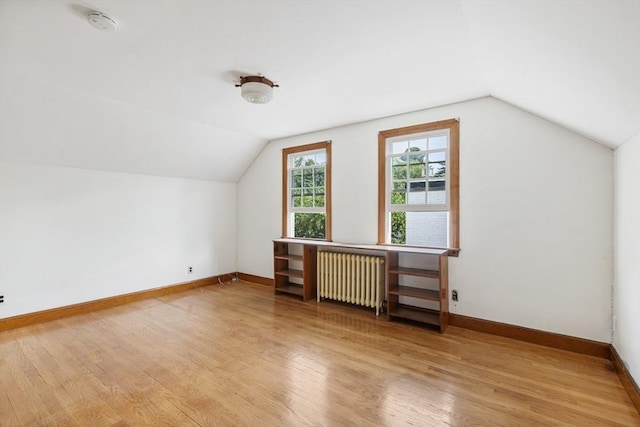 bonus room featuring light hardwood / wood-style floors, radiator, and vaulted ceiling