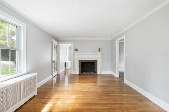 unfurnished living room with radiator, a fireplace, a healthy amount of sunlight, and light hardwood / wood-style floors