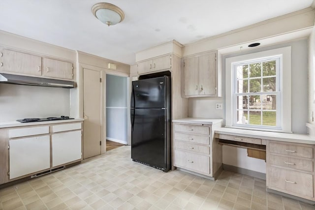 kitchen with white gas stovetop, built in desk, and black refrigerator