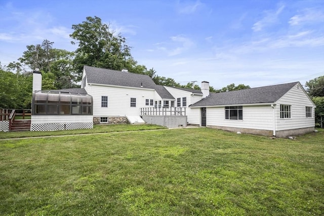 back of property with a deck, a yard, and a sunroom