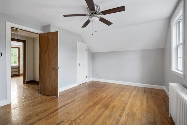 bonus room featuring ceiling fan, radiator heating unit, lofted ceiling, and light wood-type flooring