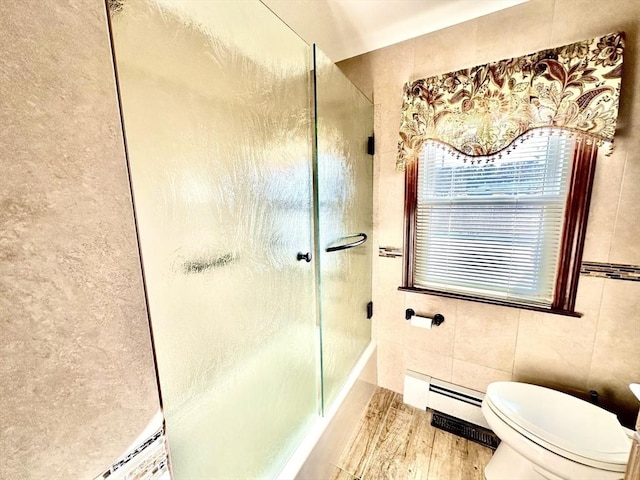 bathroom with hardwood / wood-style floors, a shower with shower door, tile walls, baseboard heating, and toilet