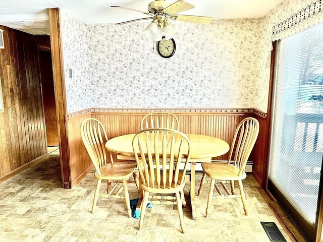 dining area with wooden walls and ceiling fan