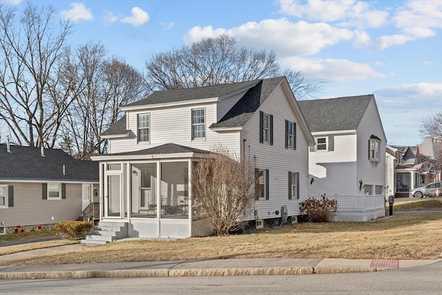 front facade featuring a sunroom and a front yard