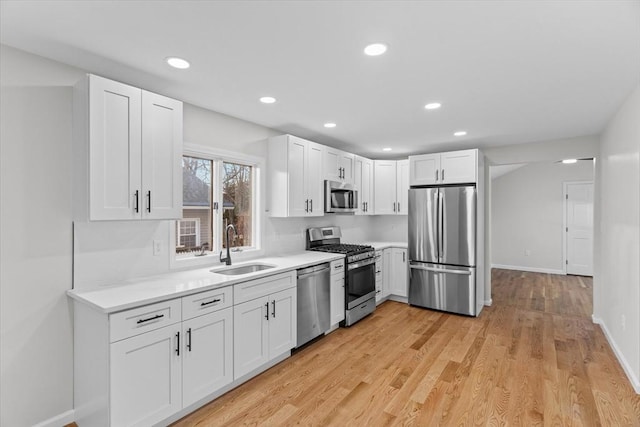 kitchen featuring appliances with stainless steel finishes, light hardwood / wood-style floors, white cabinetry, and sink