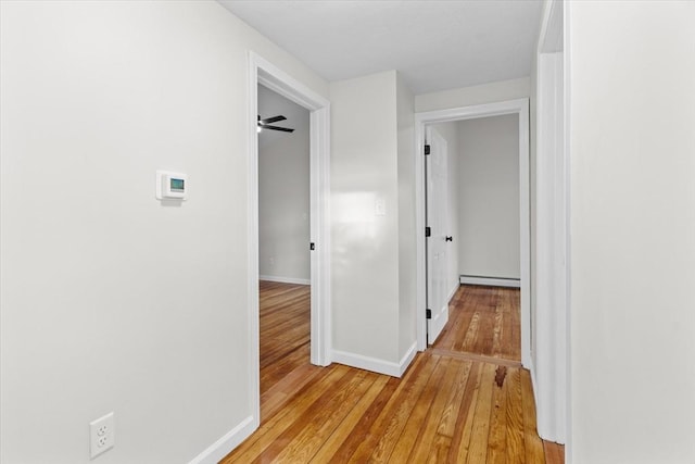 corridor with baseboard heating and light hardwood / wood-style flooring