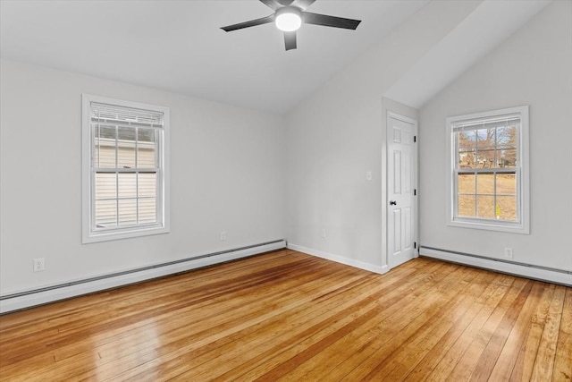 empty room featuring light hardwood / wood-style floors, baseboard heating, and vaulted ceiling