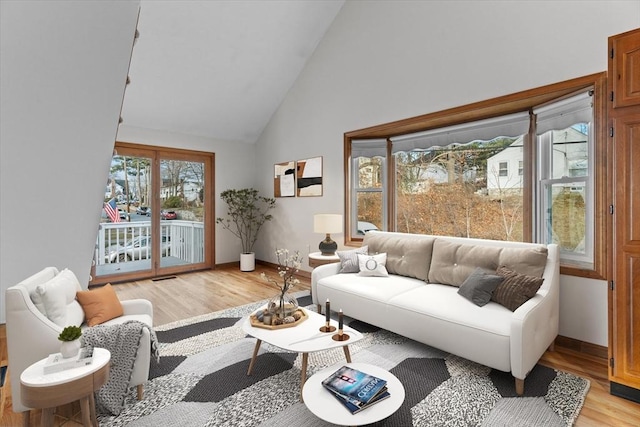 living room featuring high vaulted ceiling and light hardwood / wood-style flooring