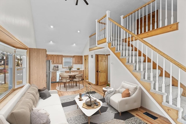 living room featuring high vaulted ceiling and light hardwood / wood-style flooring