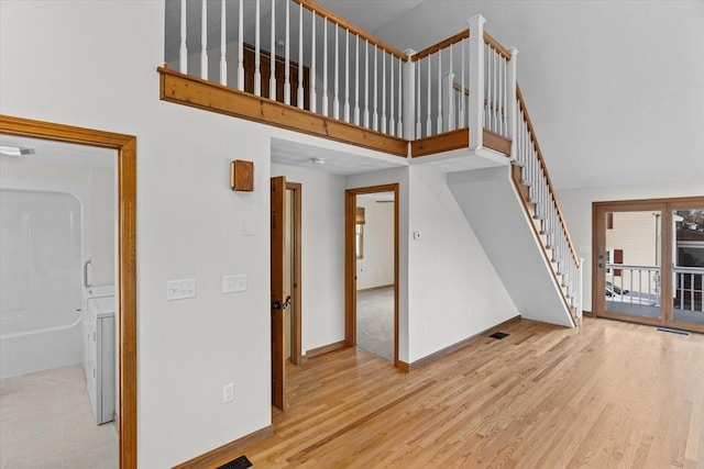 unfurnished living room featuring a towering ceiling and light hardwood / wood-style floors