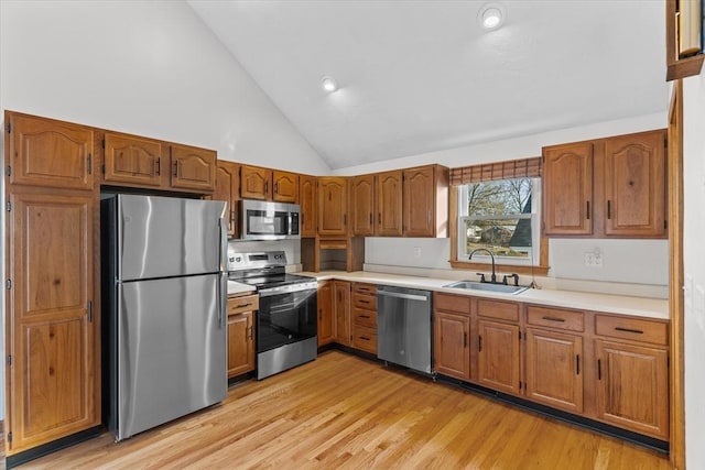 kitchen with sink, high vaulted ceiling, light wood-type flooring, and appliances with stainless steel finishes