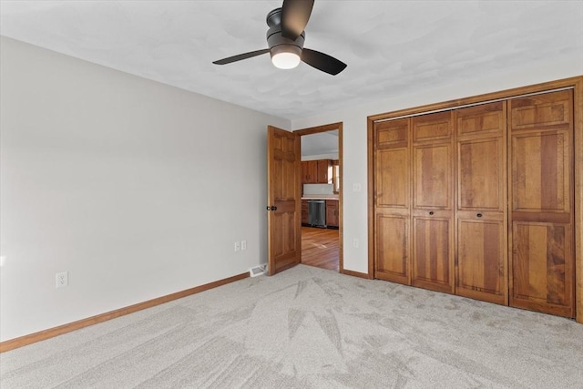 unfurnished bedroom with a closet, light colored carpet, and ceiling fan