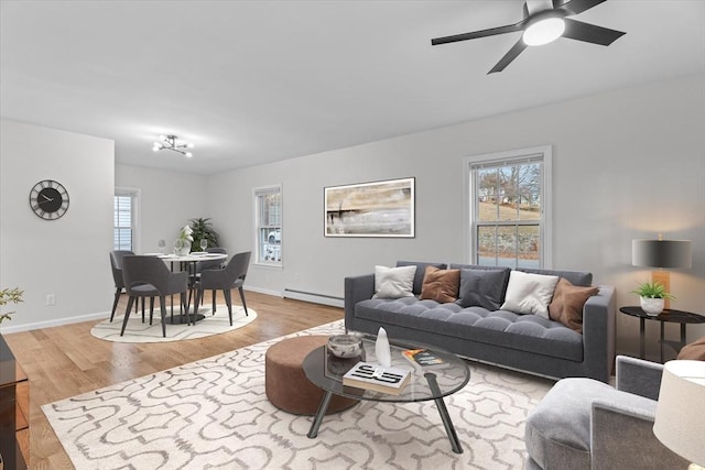 living room with ceiling fan, plenty of natural light, light hardwood / wood-style flooring, and a baseboard heating unit