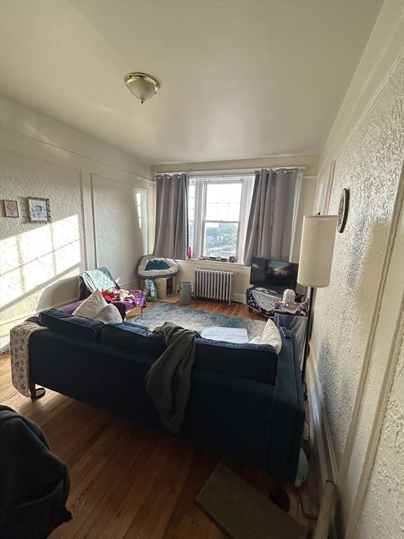1691 Commonwealth Unit 32, Boston, MA 02135 - living room featuring radiator, a textured wall, and wood finished floors