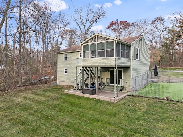 rear view of property with a yard, a patio, and a sunroom